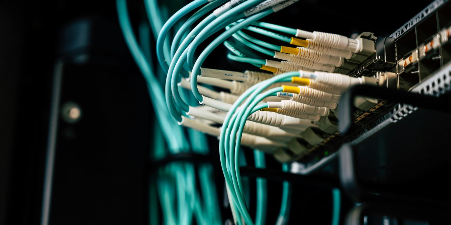 Close-up of fiber optic cables connected to a network switch, representing field operations in fiber installation.